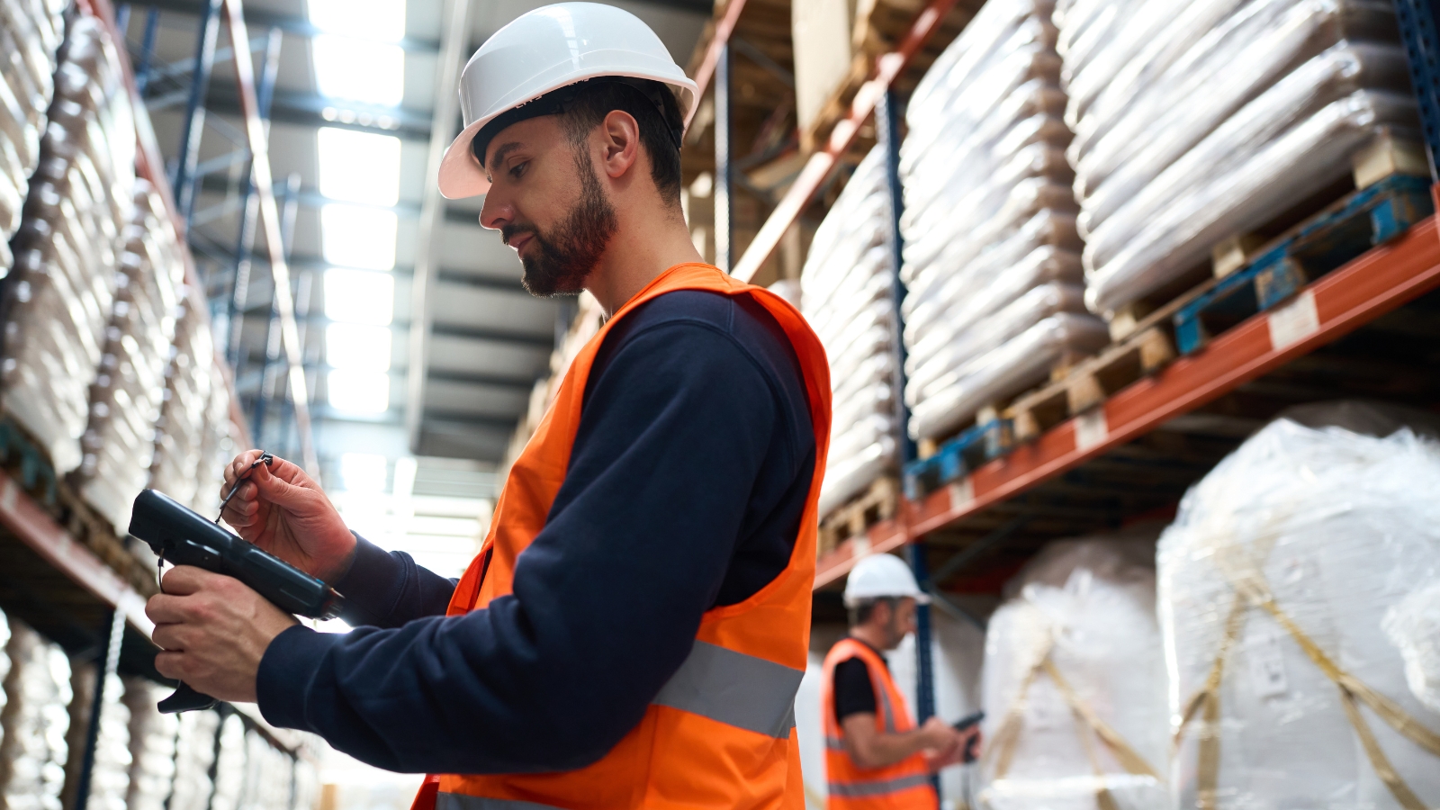 Mannelijke orderpicker in Nederlands magazijn scant product met handscanner